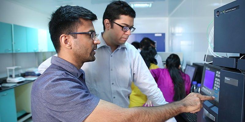Vivek Gera and early collaborator Abhishek Jha working beside laboratory equipment