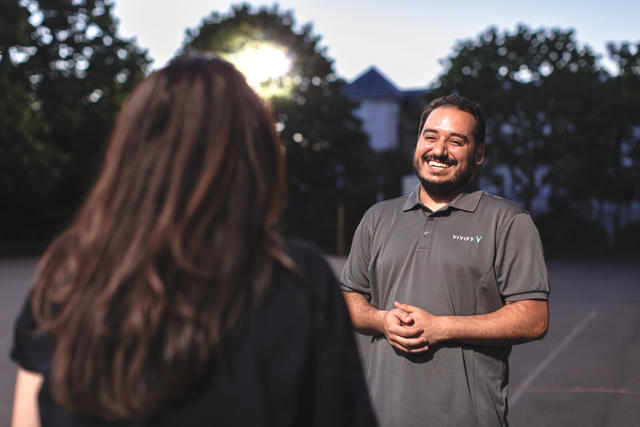 A Vivify community host speaking with a visitor outside a school facility