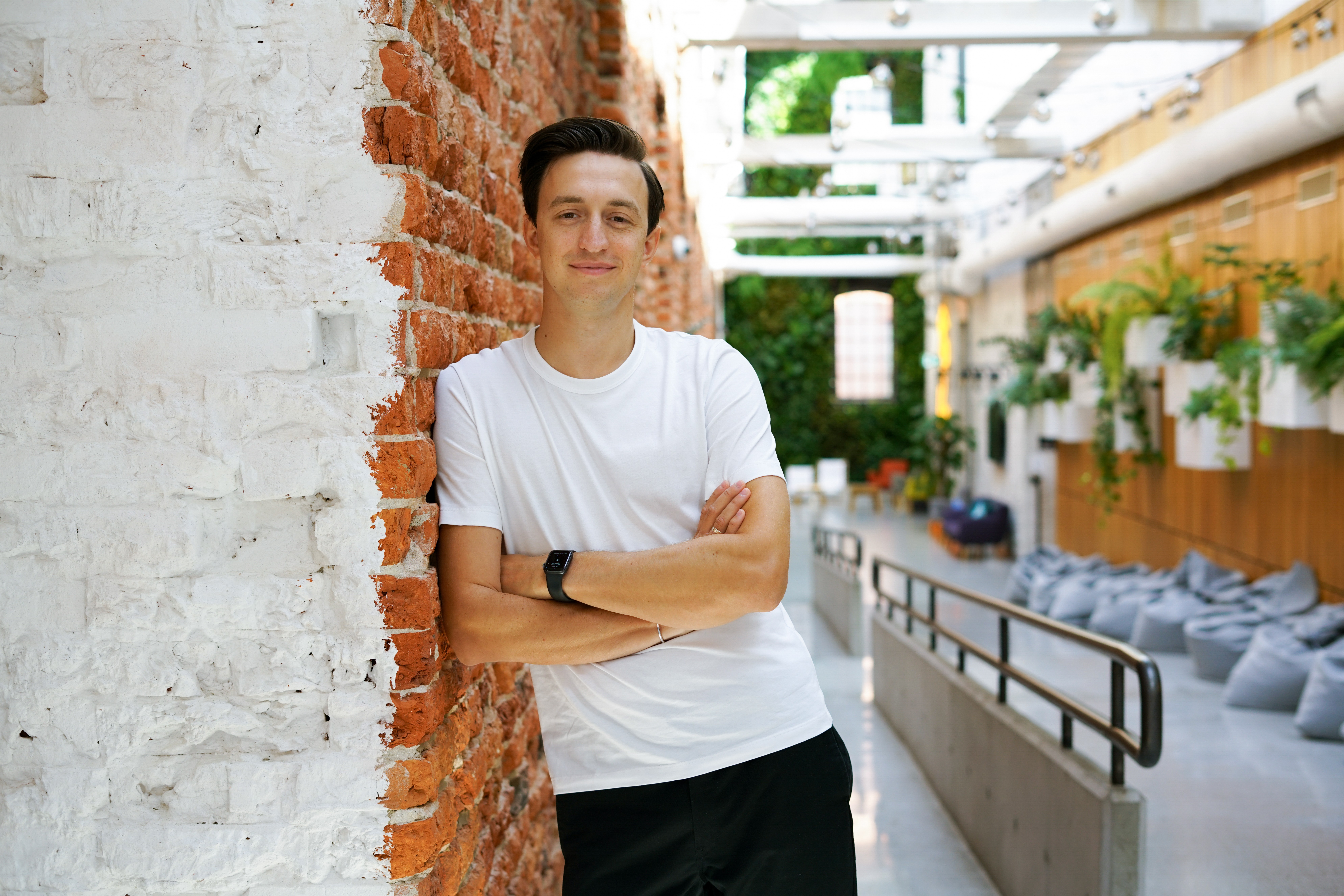 Vladyslav Podoliako standing beside an exposed brick wall in a bright interior