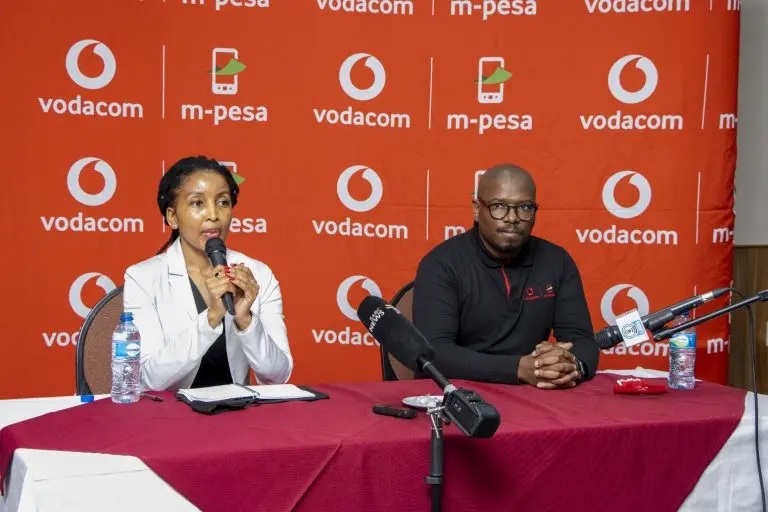 Two VCL Financial Services representatives presenting the M-Pesa app at a press event