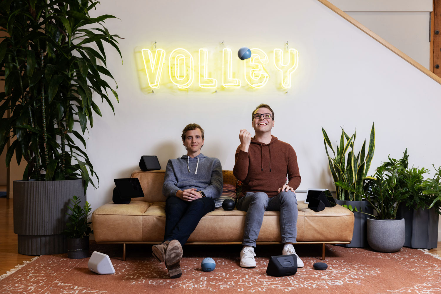 Volley co-founders Max Child and James Wilsterman seated beneath a Volley sign at their San Francisco office