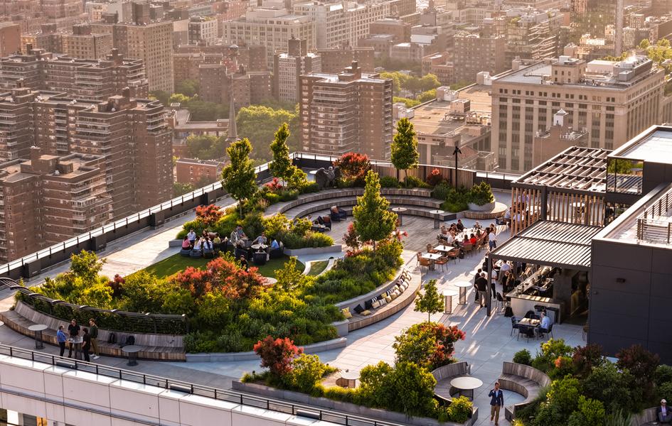 People gather among trees and seating on PENN 2’s rooftop terrace overlooking Manhattan