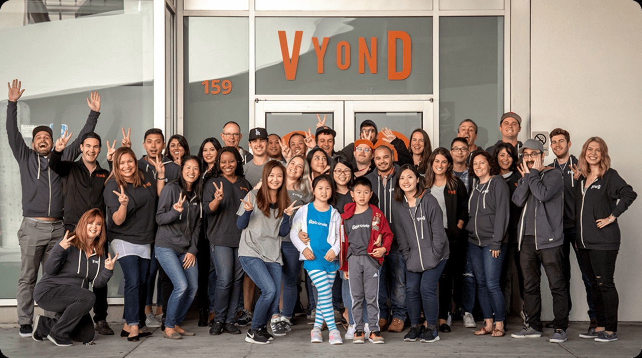 A Vyond team group posing outside an office entrance