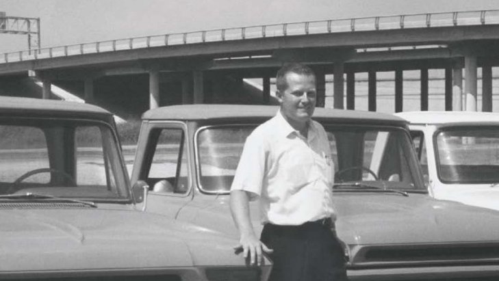 A young Marvin Rush standing among trucks beneath a highway overpass