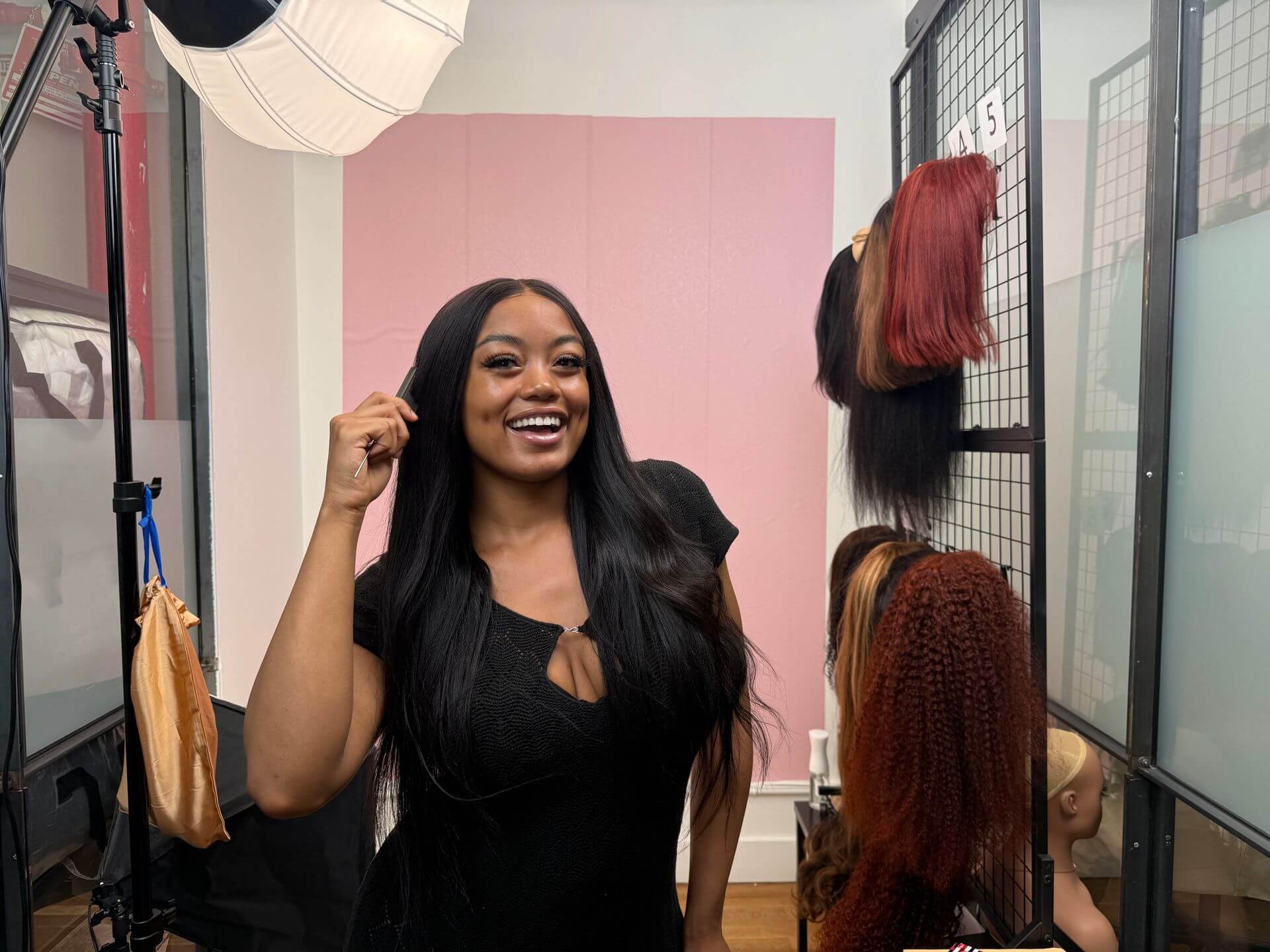 A presenter beside wig samples and lighting in a Wahool demonstration setup