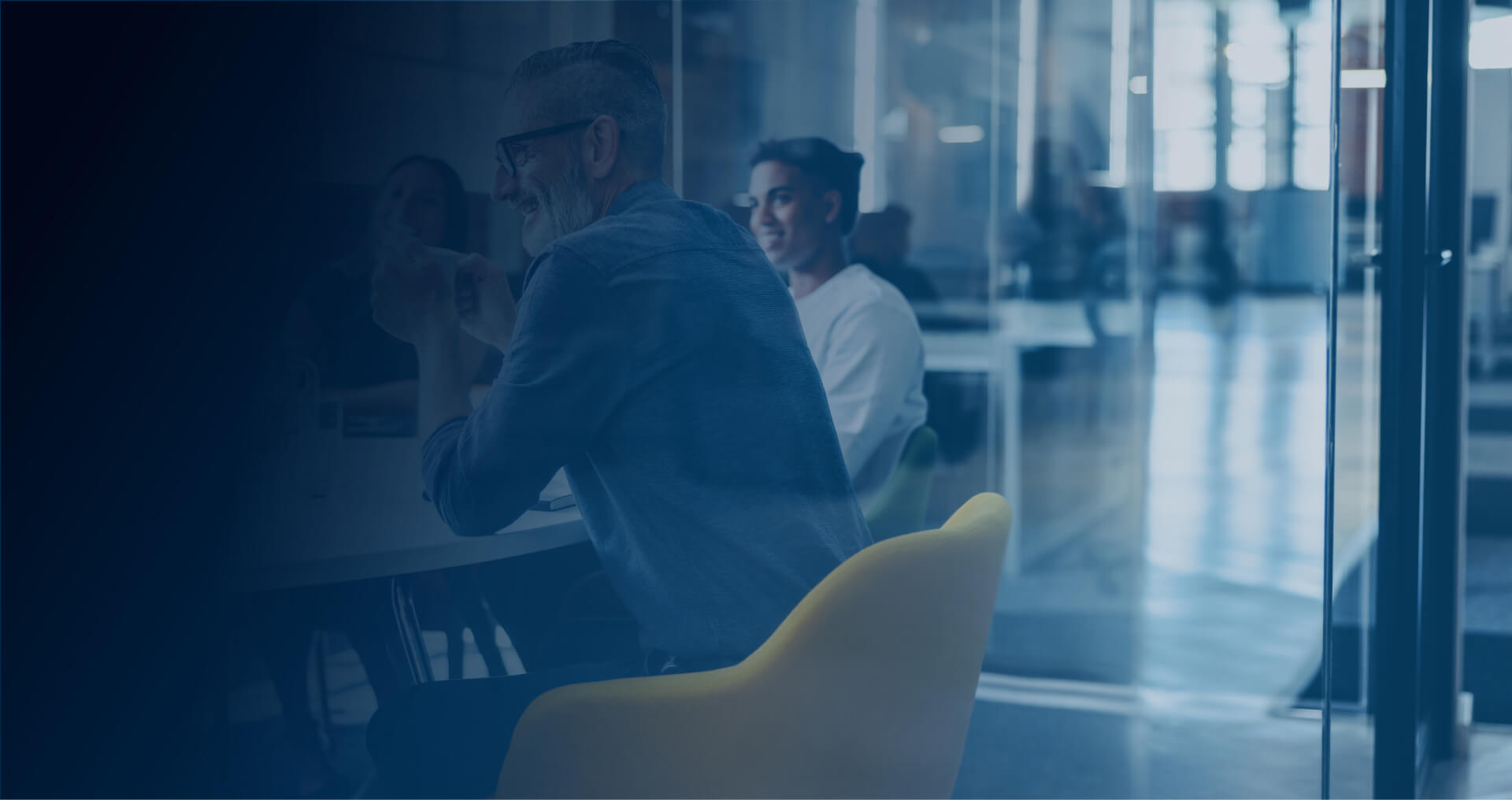 Colleagues talking around a table in a glass-walled office
