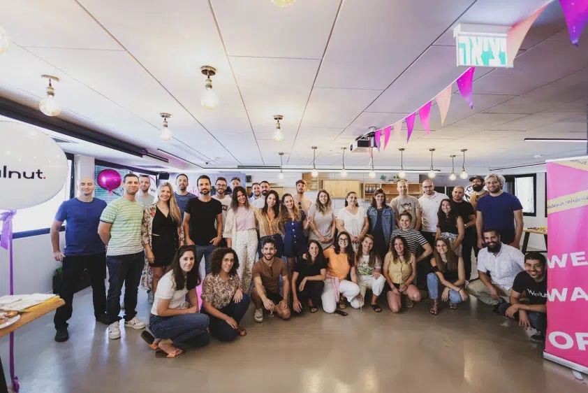 Walnut team members gathered beneath pink bunting in an office