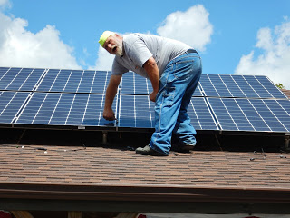 Walter Kreuser placing a solar panel on the country store roof in 2016