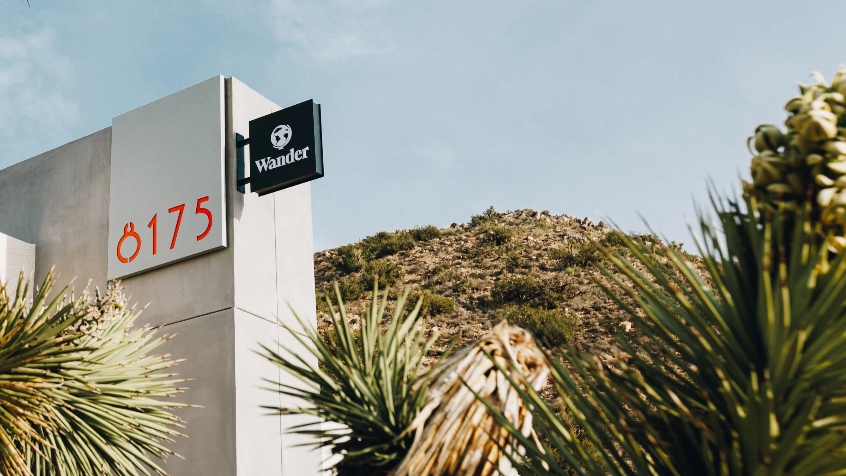 Wander property entrance with a company sign and desert landscaping