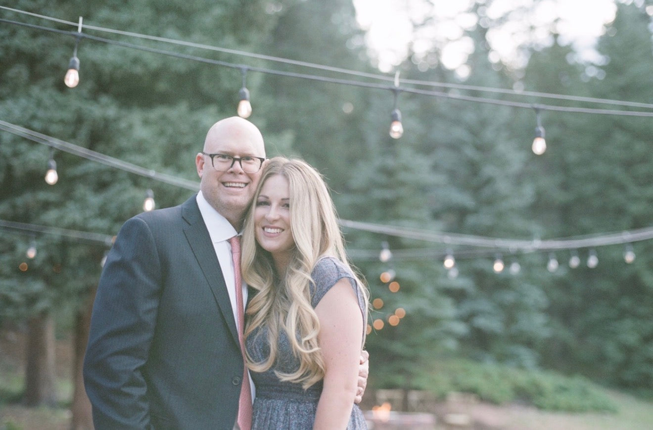 Ward and Sarah Komers smiling outdoors beneath string lights