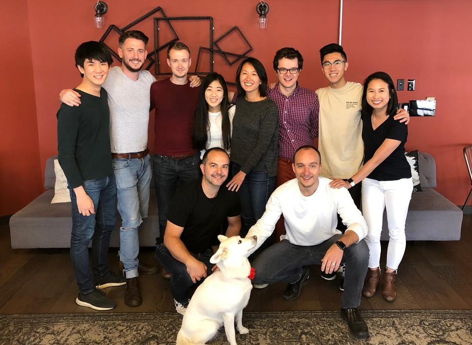An early Empower team photograph, with colleagues gathered around a sofa and a dog