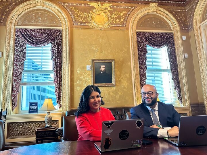 Radhika Shah-Meade and Wasim Khaled seated with laptops in an ornate room at the White House