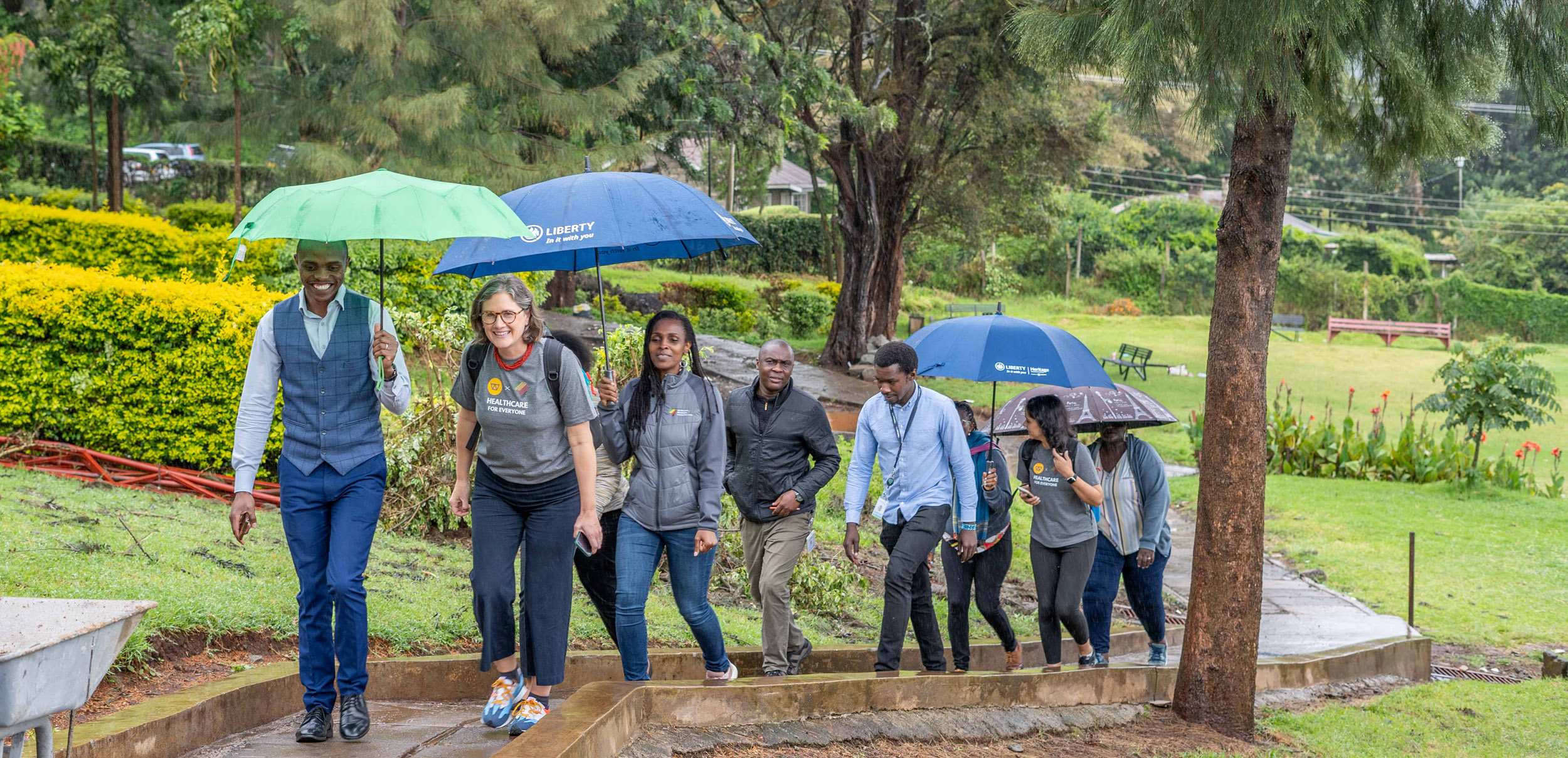 Watsi staff and healthcare partners walking together under umbrellas in East Africa
