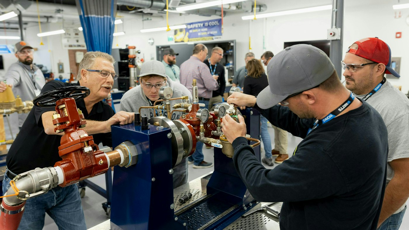 Watts instructor and trainees examine a working valve assembly during hands-on training
