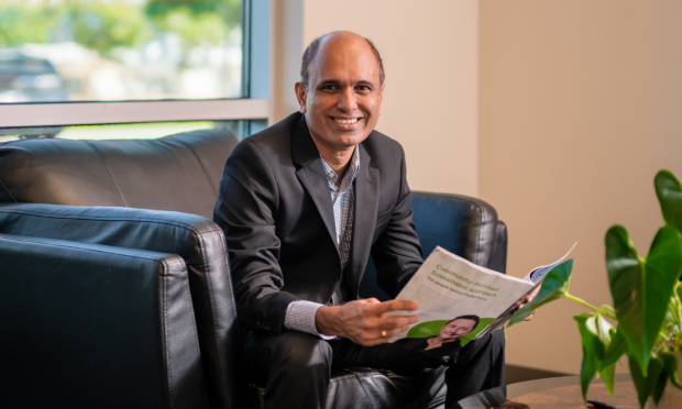 Way.com co-founder Binu Girija sitting on a sofa with a magazine
