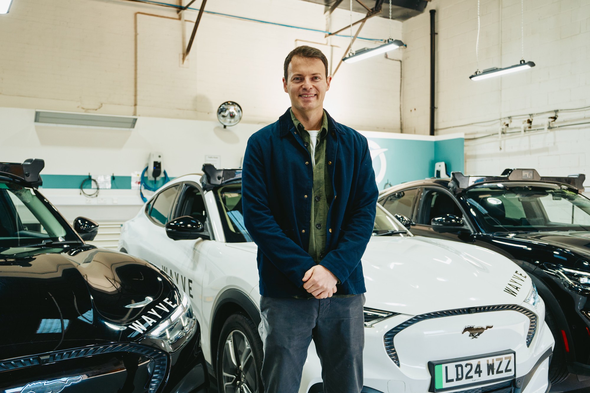 Wayve co-founder and CEO Alex Kendall beside a company vehicle