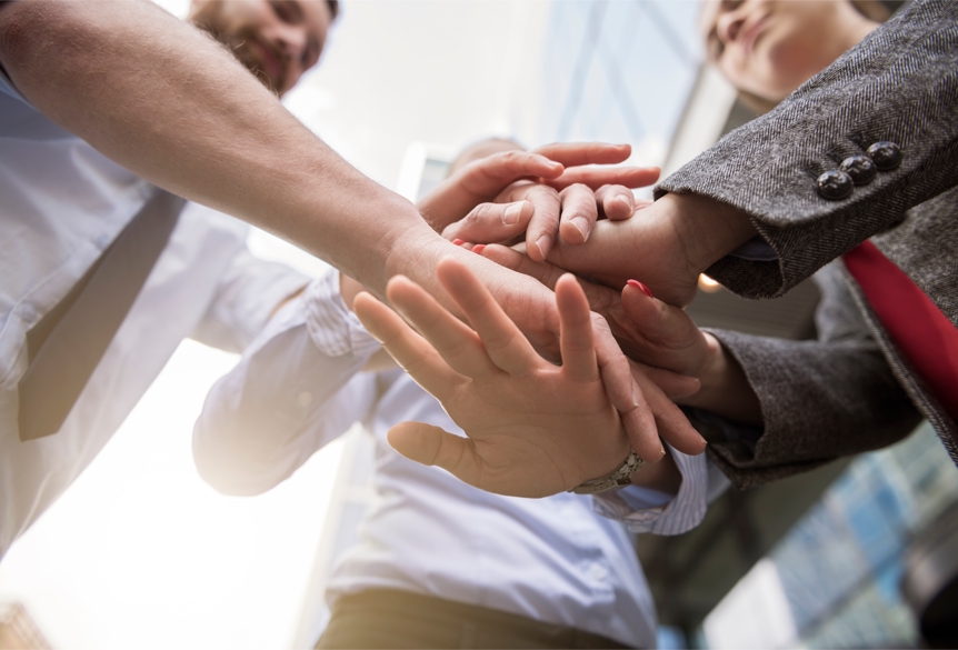 Team members stacking their hands together in a company photograph