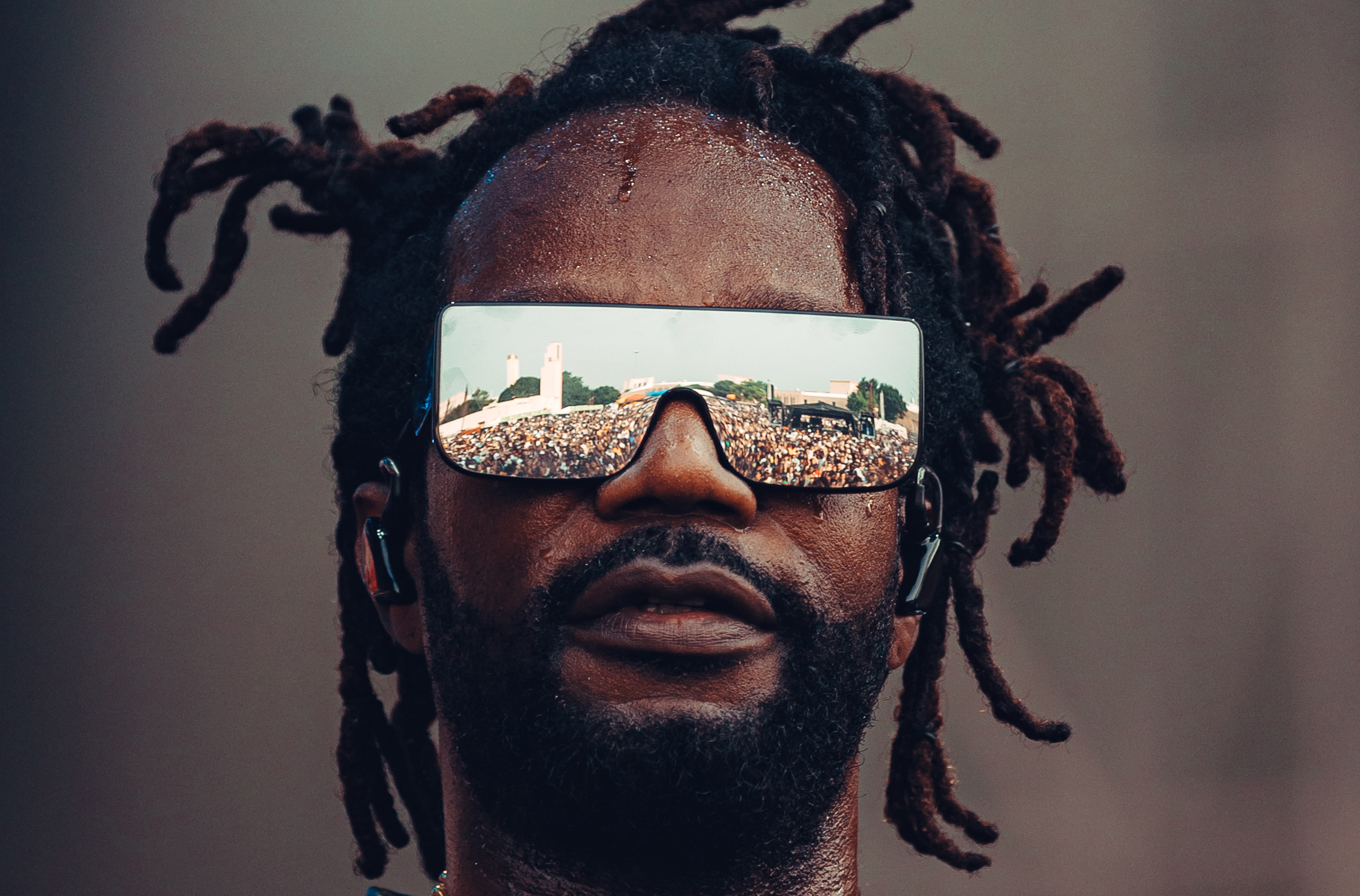 A musician wearing mirrored glasses that reflect a festival crowd