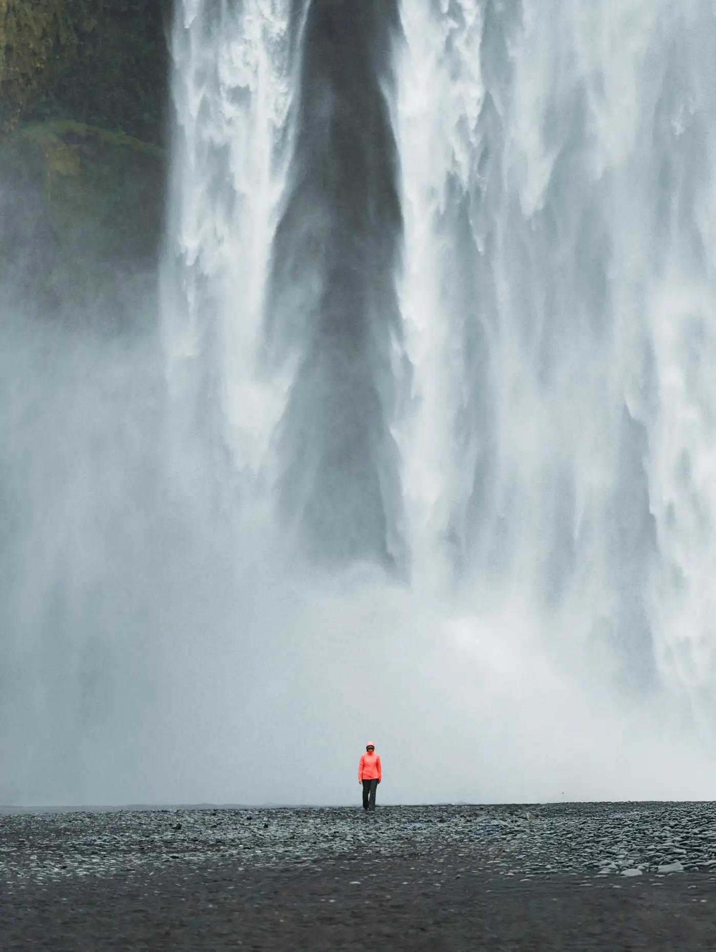 Traveler standing before a waterfall in a promotional image from WeatherPromise