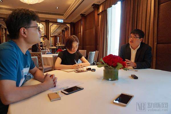 Wei Zhou, seated at right, speaking with interviewers at a table in Hong Kong