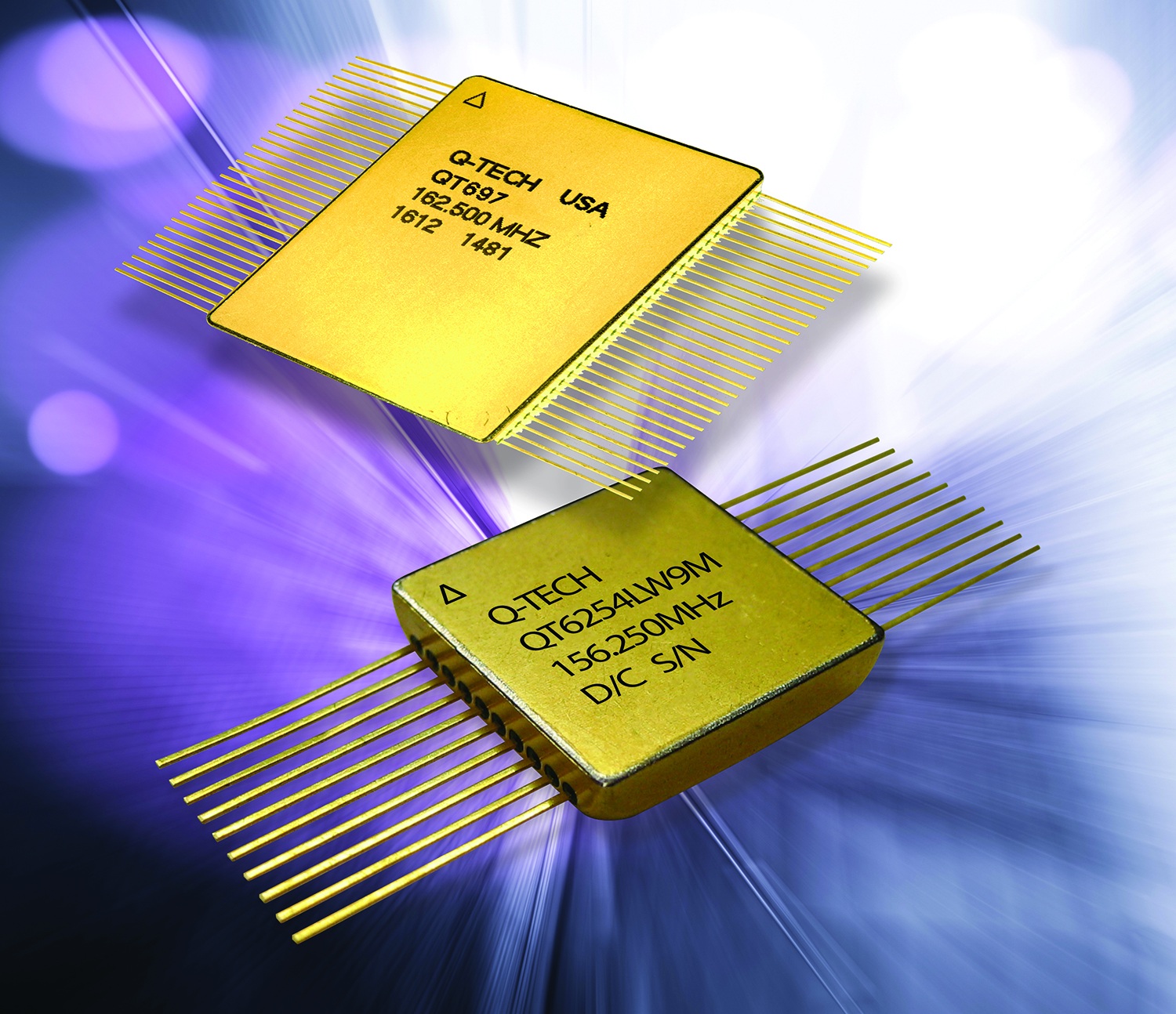 Two gold Q-Tech oscillator packages with fine metal leads, in the product publicity image accompanying its inventory announcement