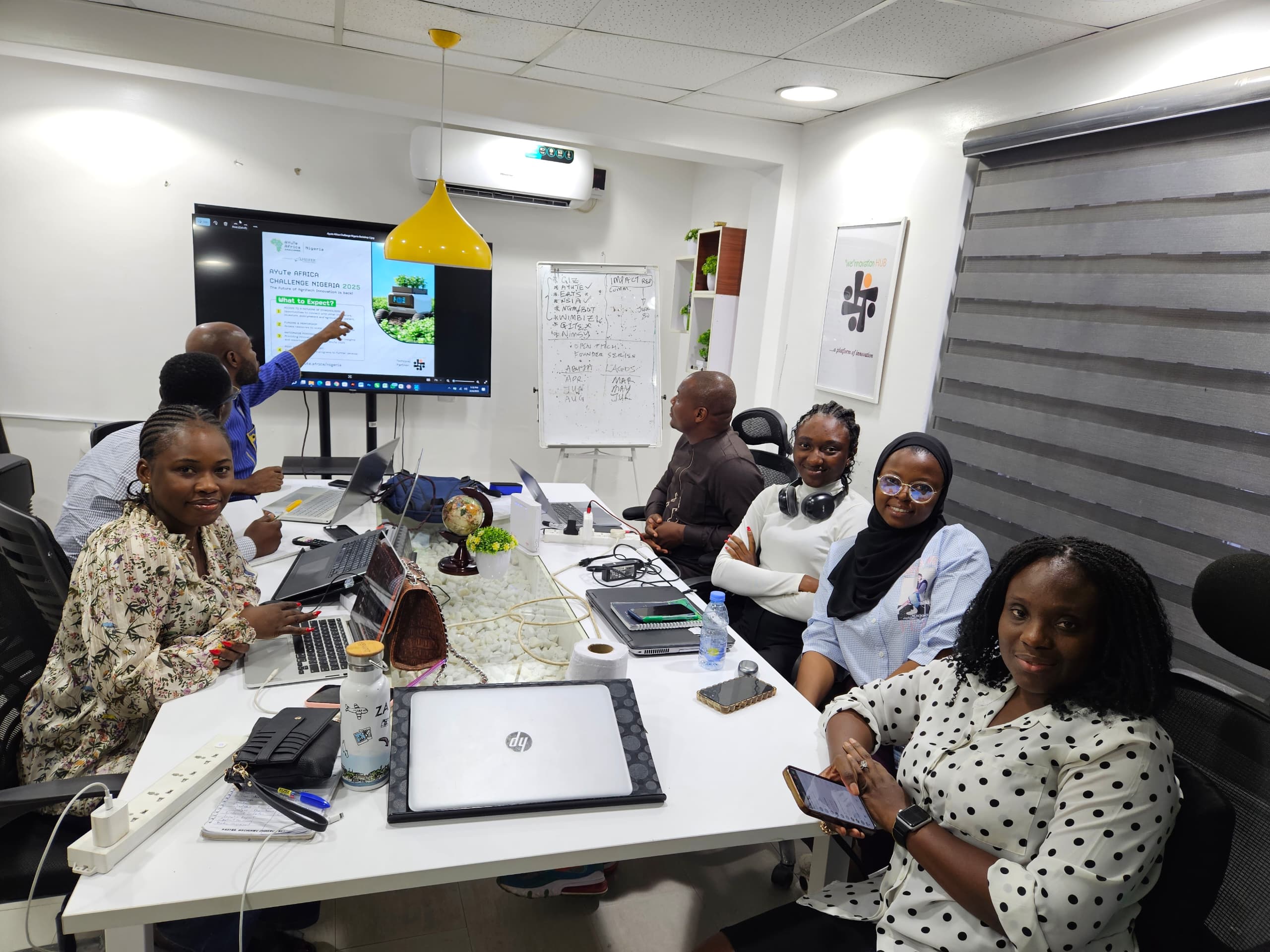 Wennovation Hub team gathered around a table with laptops and an agricultural innovation presentation on screen