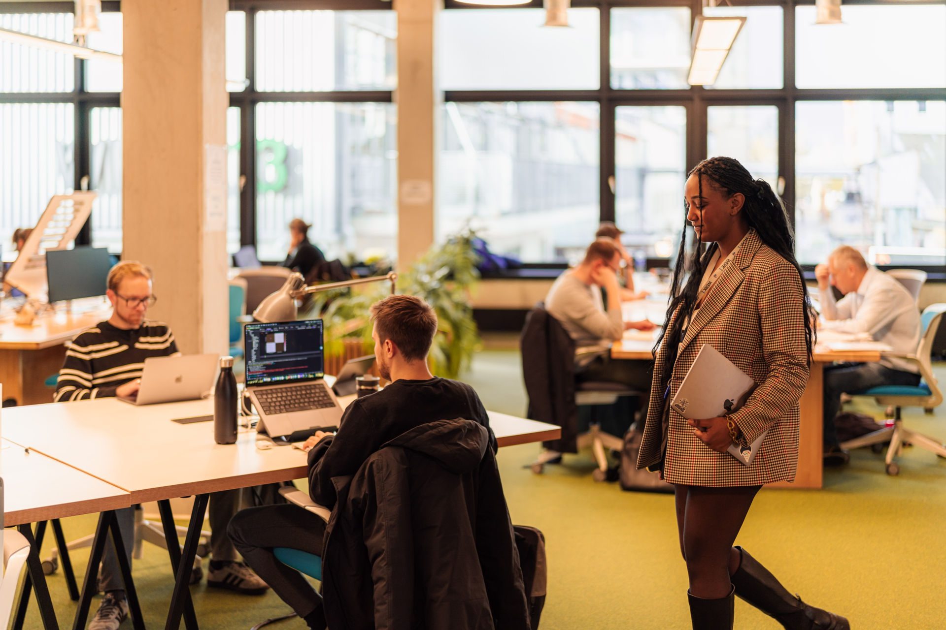 People working at shared tables in WERK1’s bright coworking space