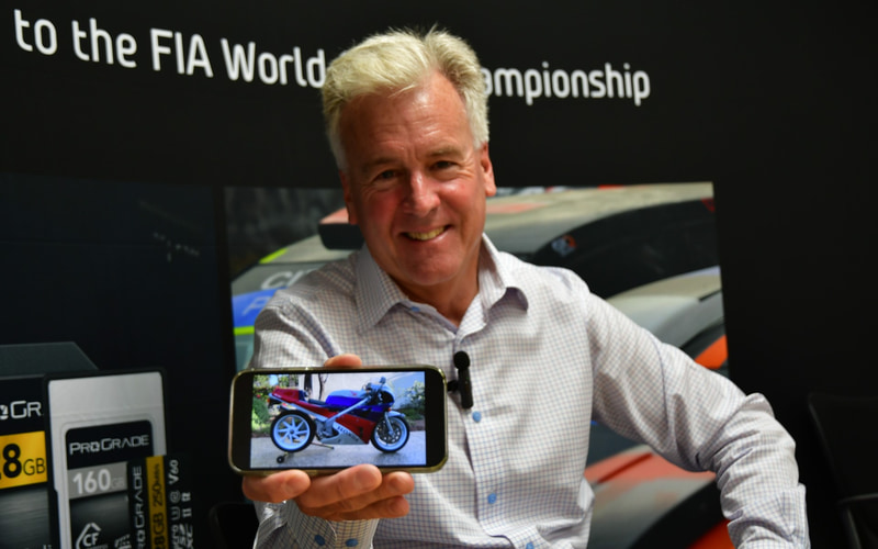 Wes Brewer smiling and displaying a photograph of his Honda RC30 motorcycle on his phone