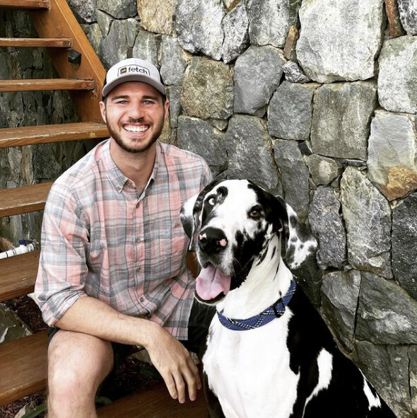 Wes Schroll sitting outdoors beside his Great Dane, Pico
