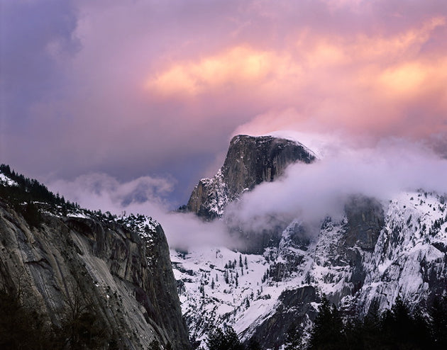 Half Dome emerging through snowy clouds beneath a pink and gold sky, photographed by Rich Seiling