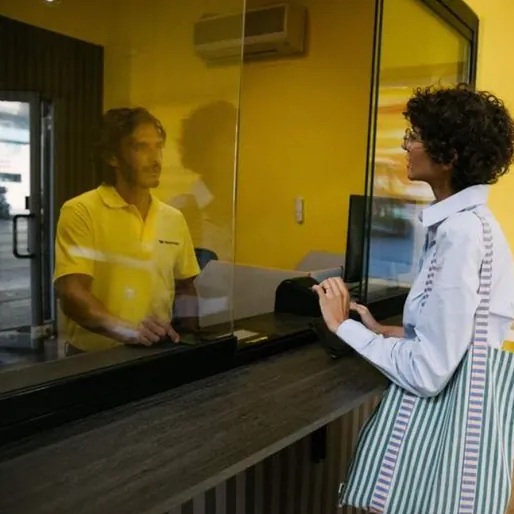 A customer speaking with an agent through the glass at a Western Union counter