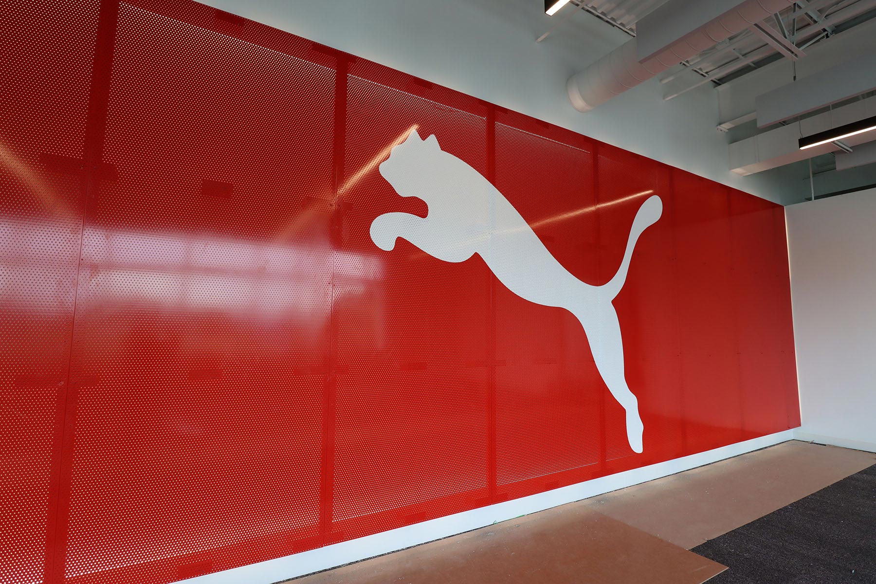 Large white Puma cat logo on a red interior feature wall