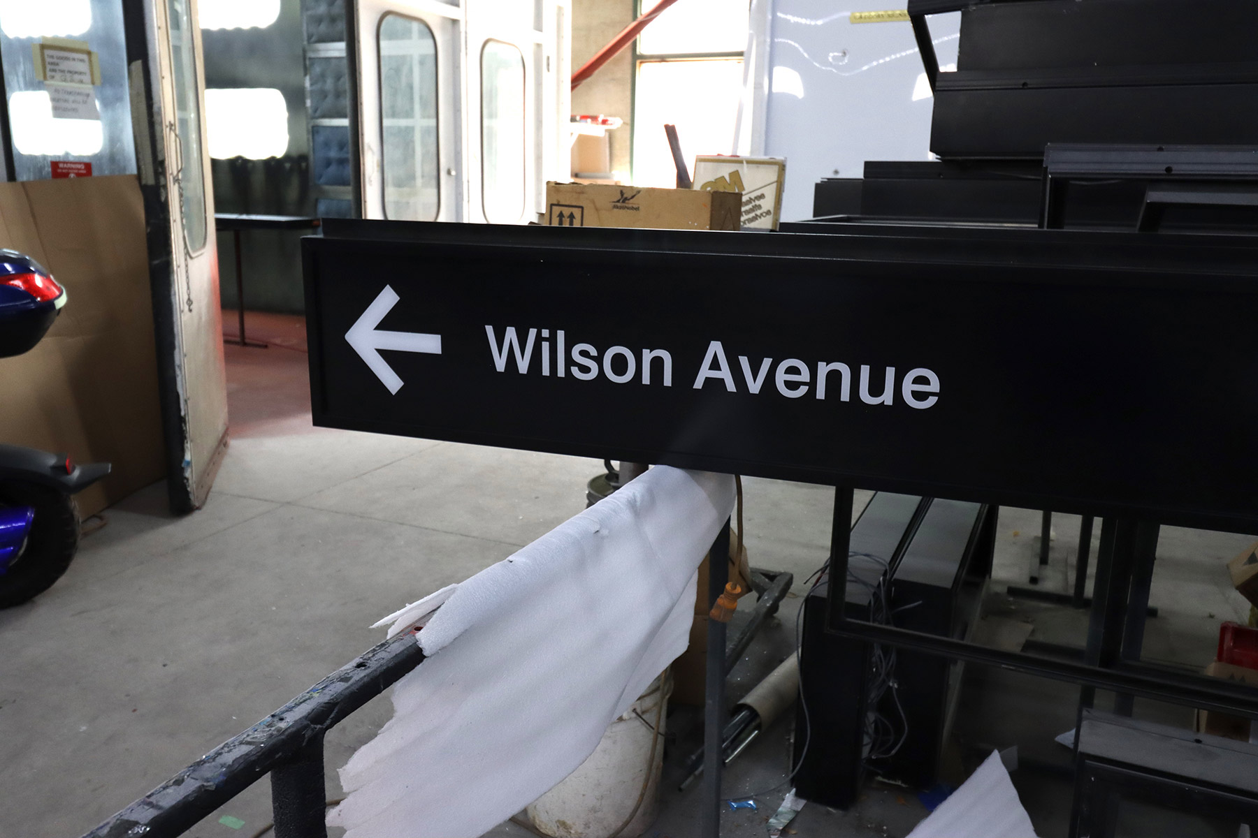 A black Wilson Avenue sign with a white left arrow in the Gregory Signs workshop