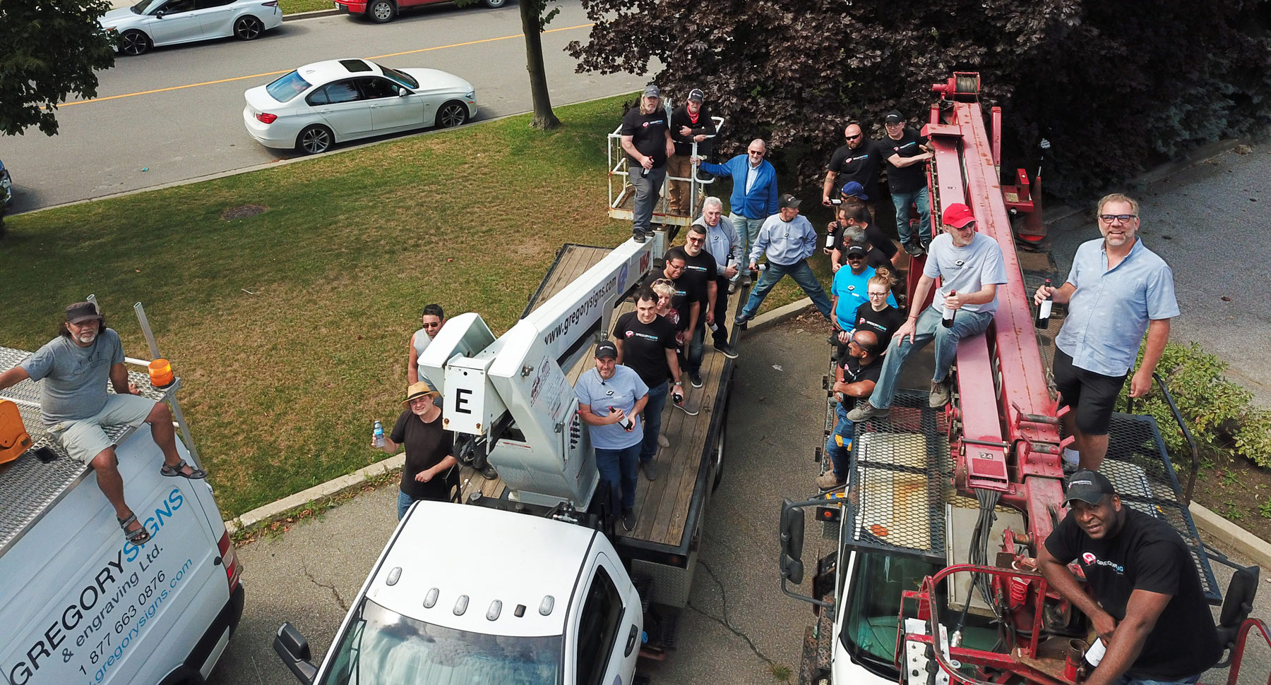 Gregory Signs staff gathered around branded installation trucks
