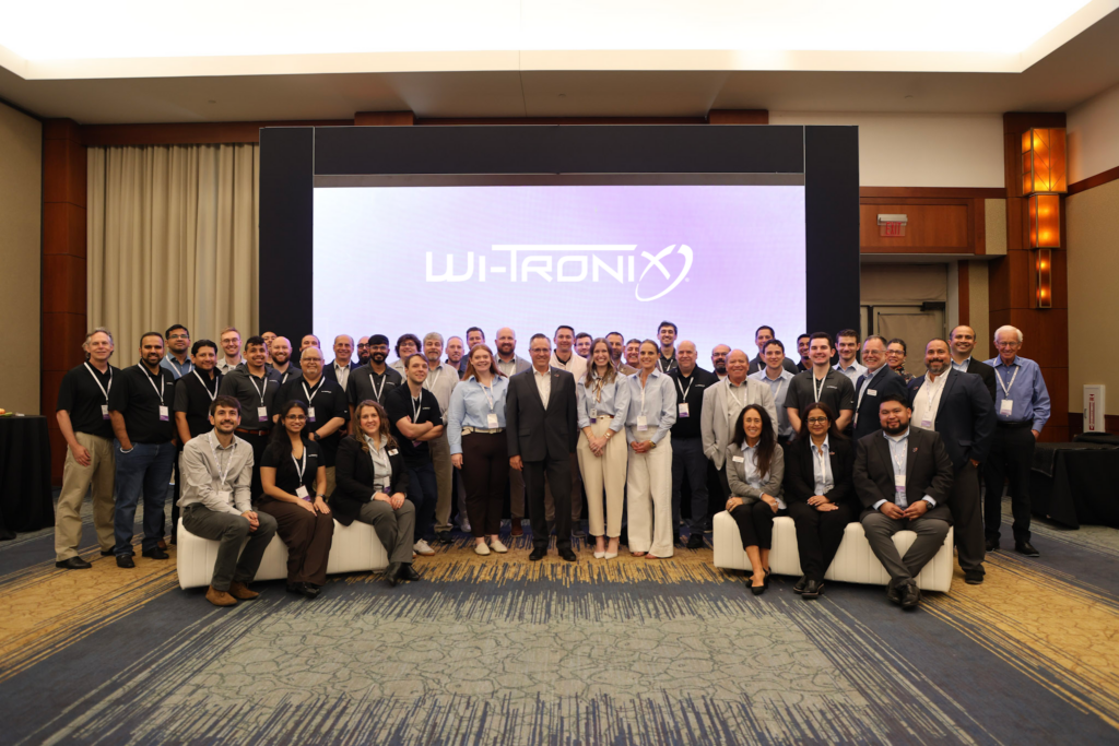 Group pictured at a Wi-Tronix event, with the company name on a screen behind them