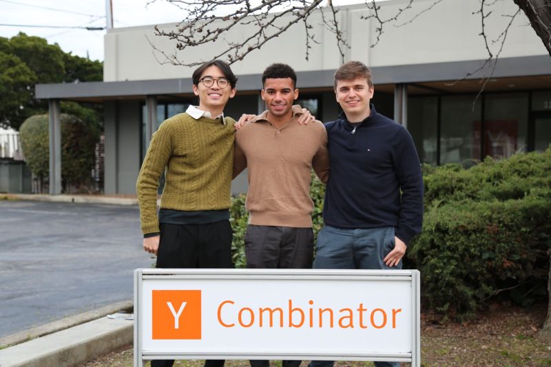 AfterQuery's three founding team members standing behind a Y Combinator sign
