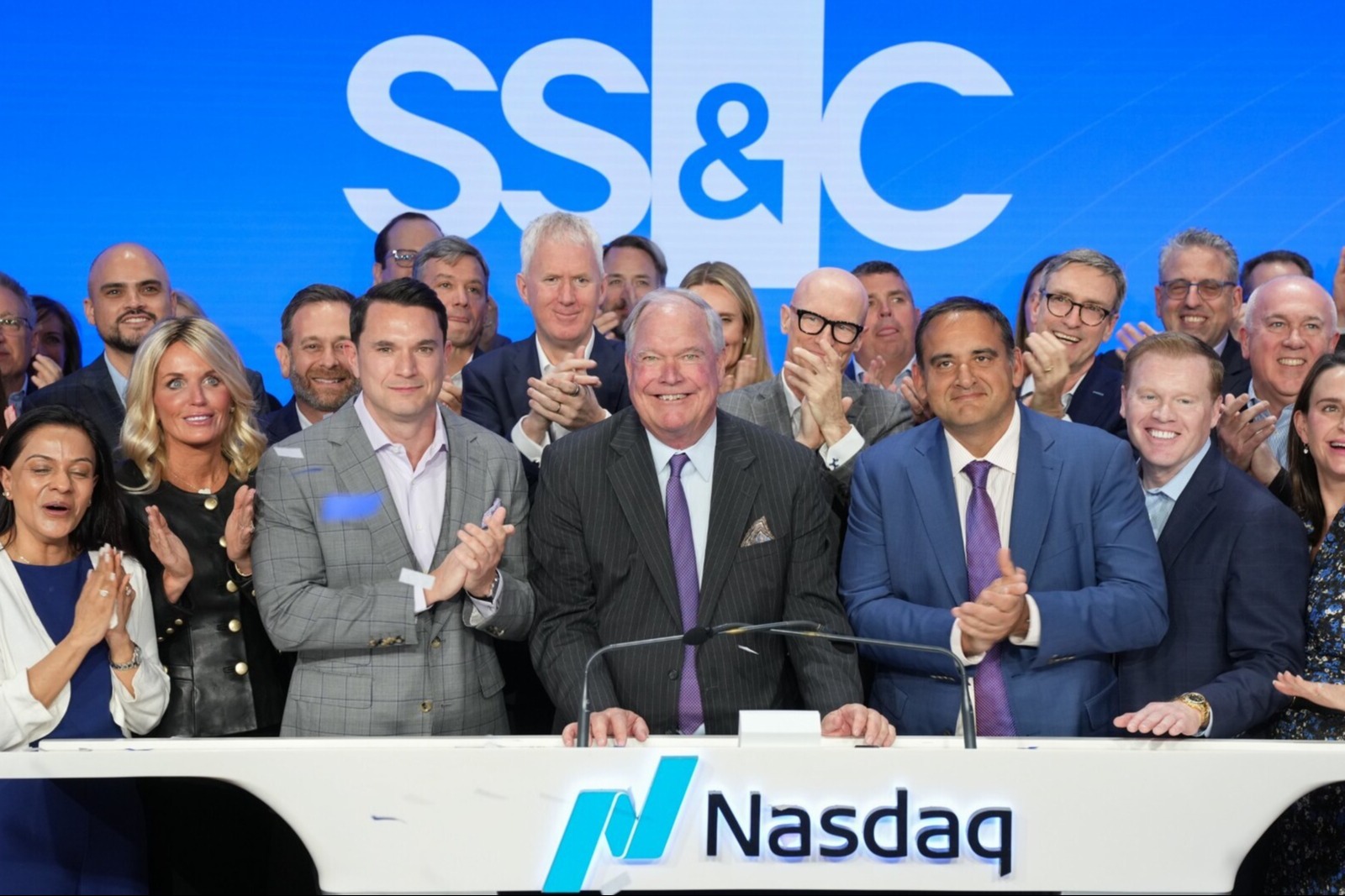 Bill Stone at the Nasdaq podium surrounded by SS&C colleagues during the company's anniversary celebration