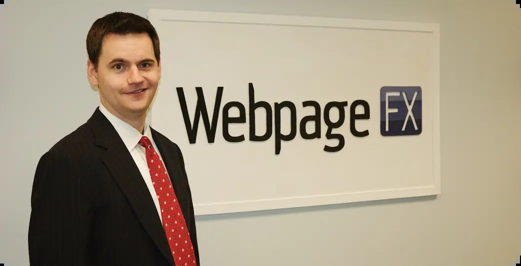 A young William Craig in a suit standing beside the WebpageFX sign