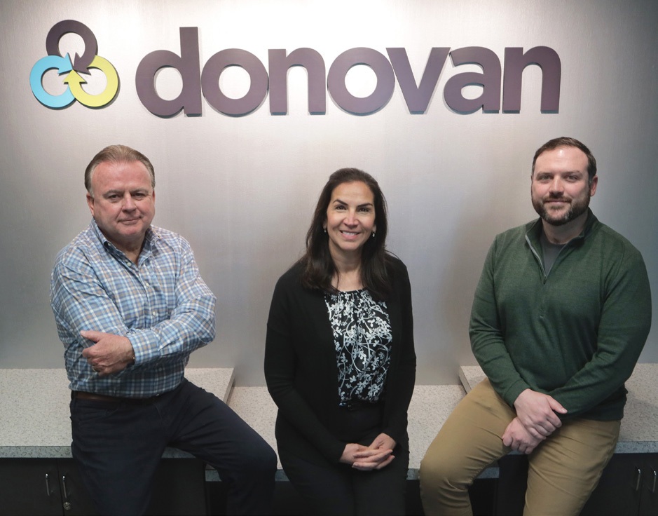 Bill Donovan, Lizette Dubacher and Ryan Donovan seated beneath the Donovan agency sign