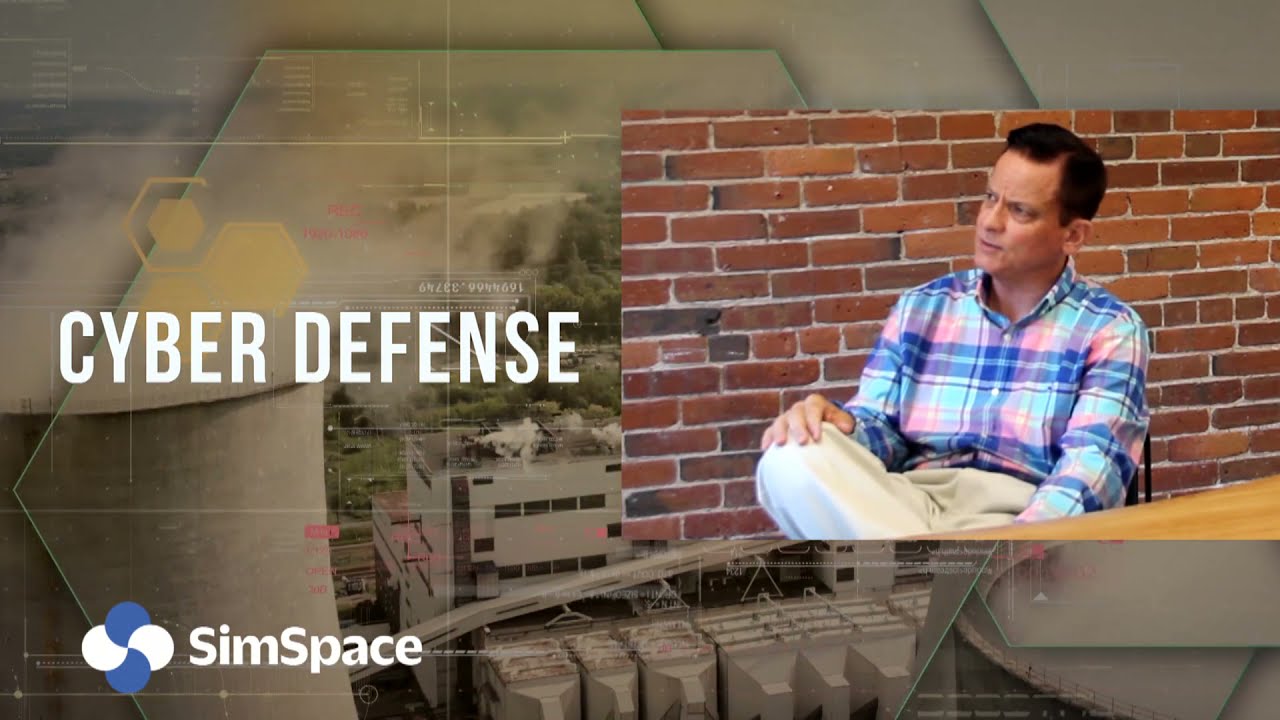 Hutchison, seated in a plaid shirt against a brick wall, in SimSpace’s interview video