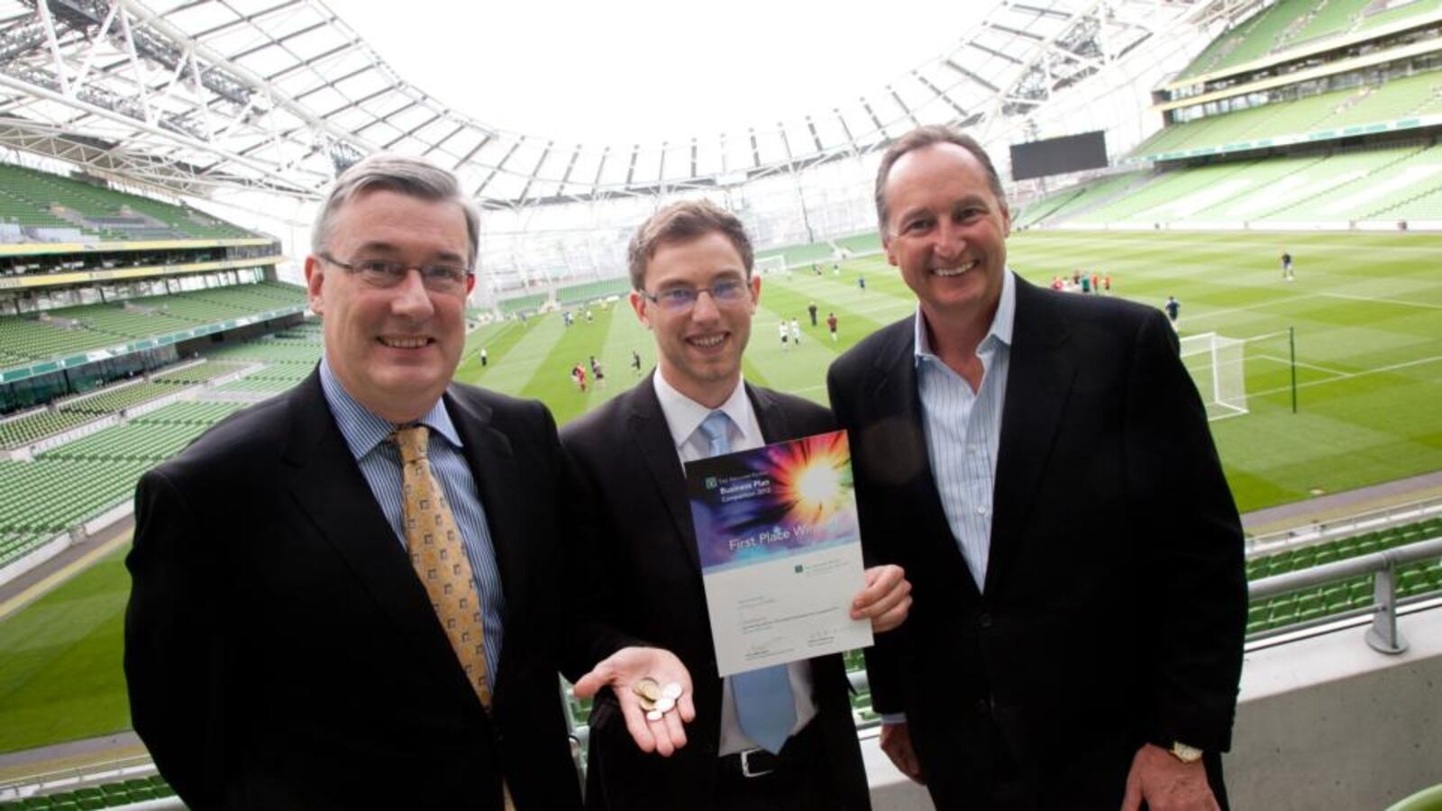 Kieran McLoughlin, Lukas Decker and Bill McKiernan standing at Dublin’s Aviva Stadium; Decker holds his competition certificate