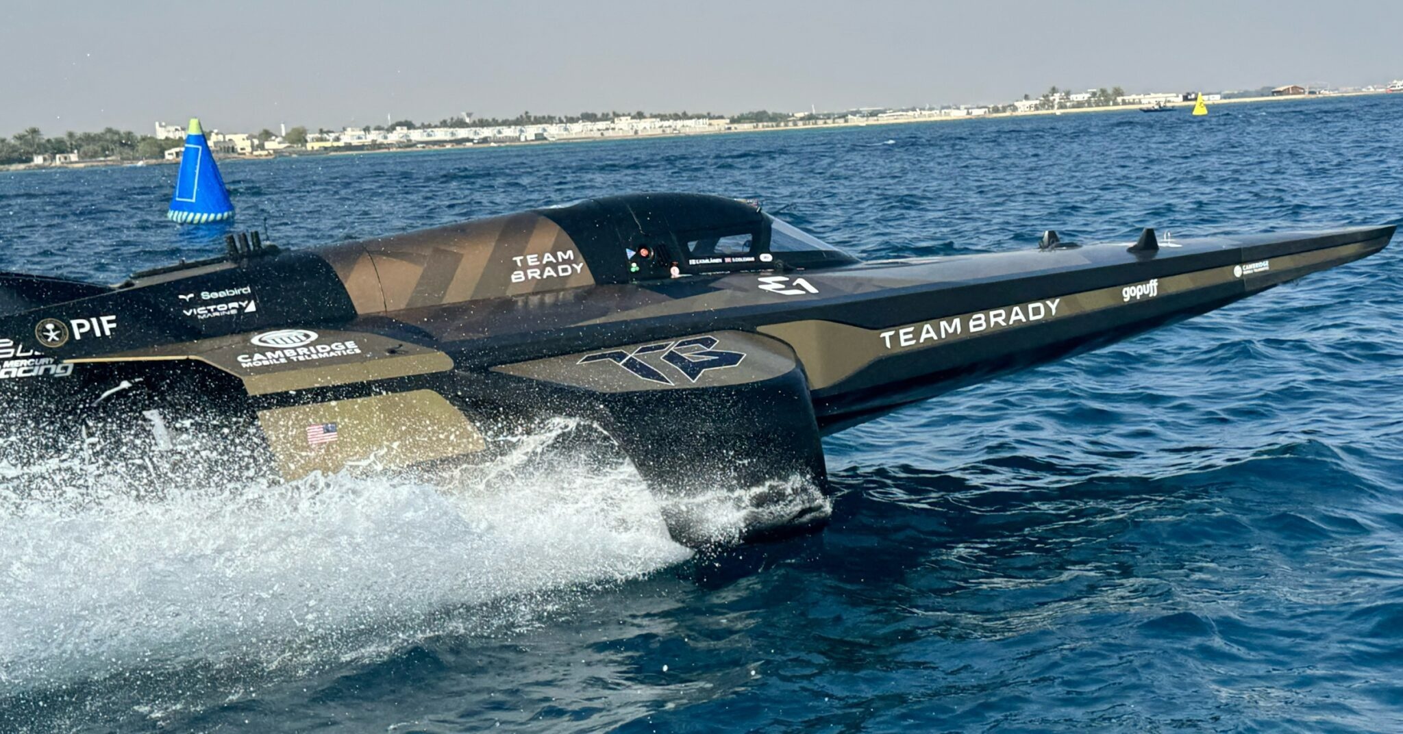 Team Brady’s black and gold electric raceboat, carrying Cambridge Mobile Telematics branding, on the water