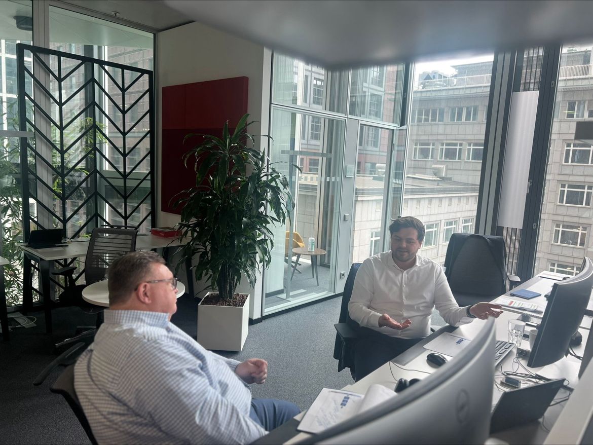 Two colleagues in conversation at an office desk in a photograph shared by Rabl from Frankfurt