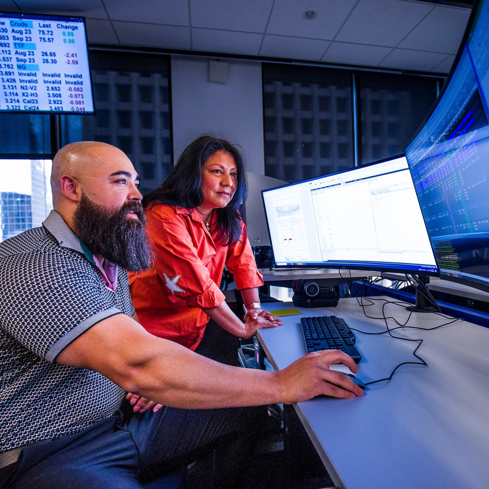 Two Sequent employees working together at a bank of trading and scheduling screens