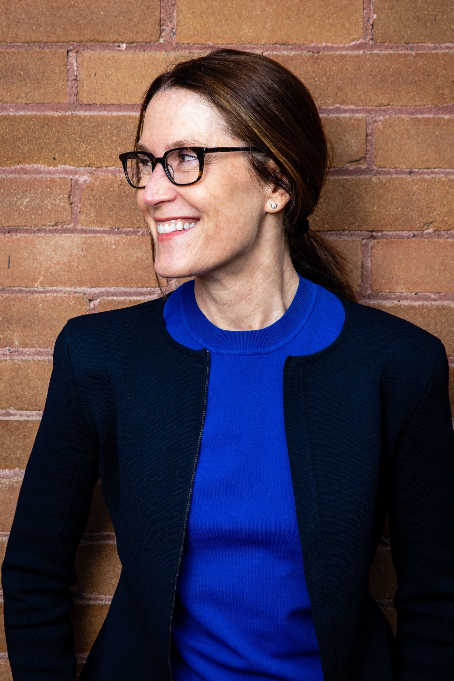 Whitney Williams, founder and CEO of williamsworks, smiling against a brick wall