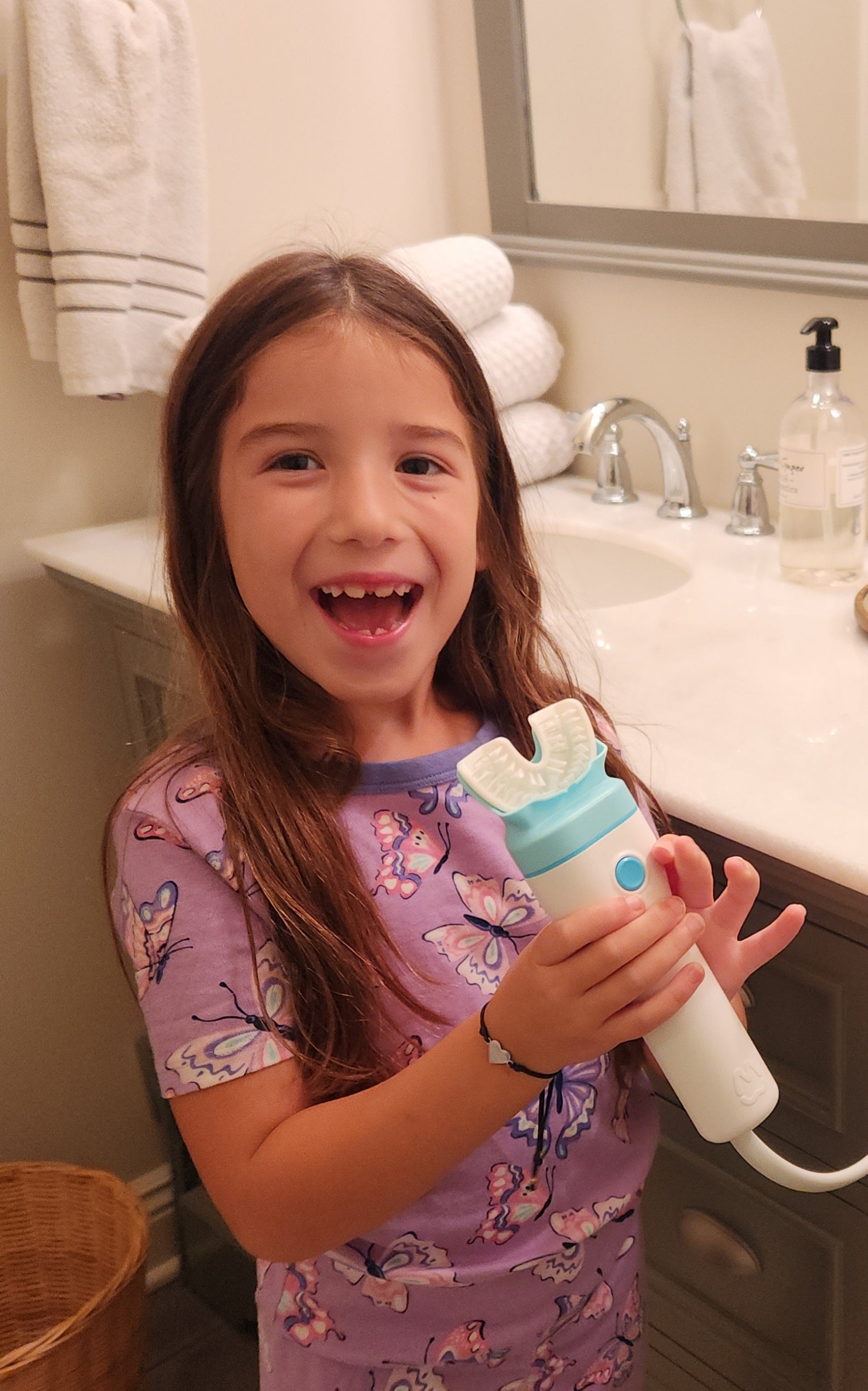 A child in butterfly pajamas holding a Willo automatic toothbrush