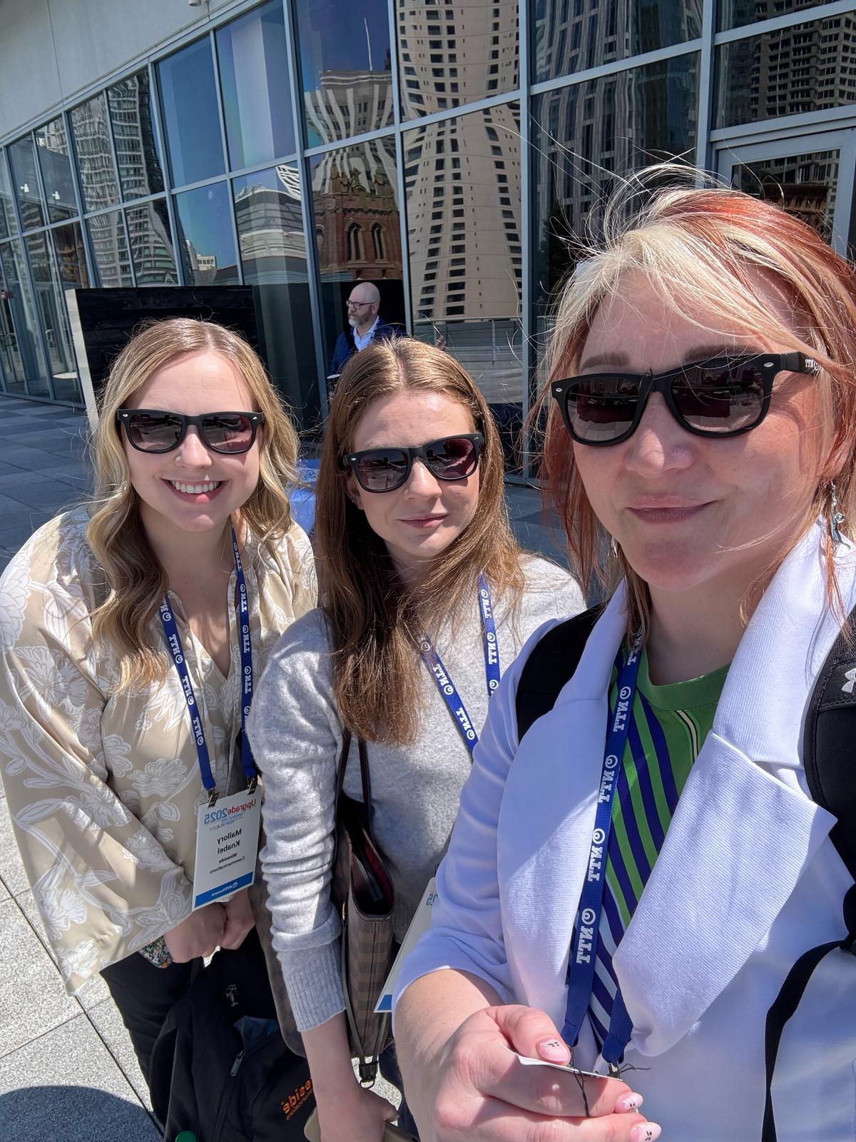 Three Wireside team members wearing NTT event badges outside the Upgrade 2025 venue in San Francisco