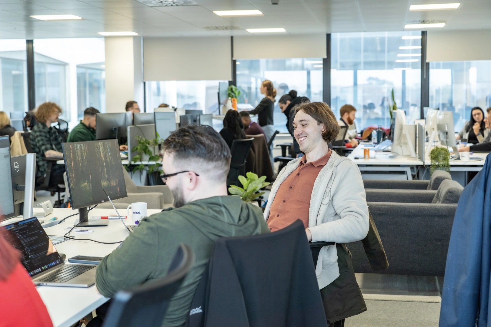 Wise employees working and talking at desks in an open-plan office