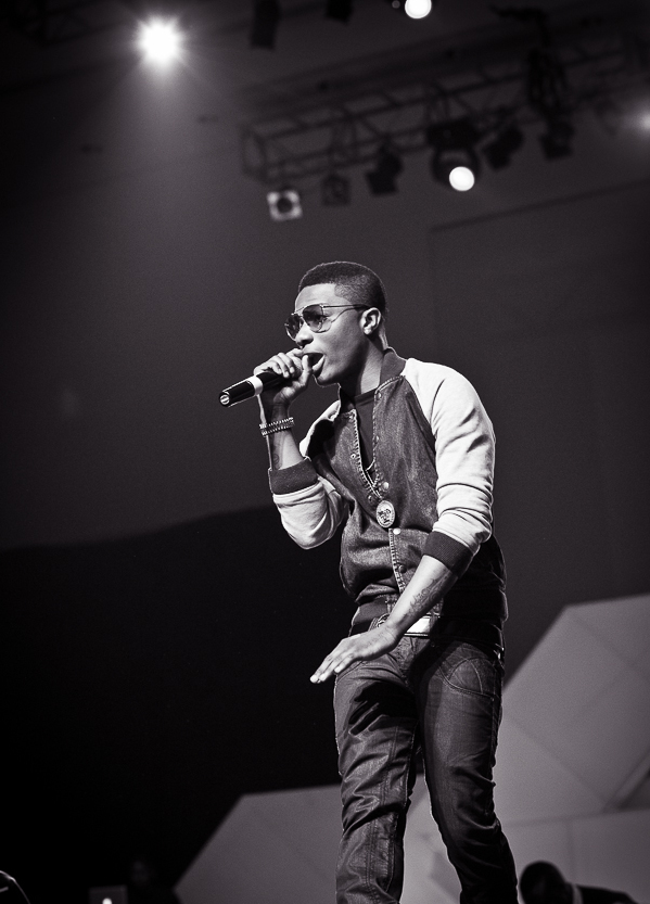 Wizkid performing onstage with a microphone in 2013