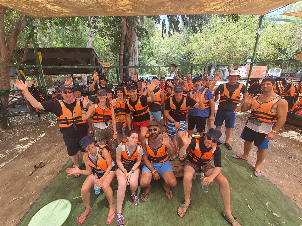 Wochit team members waving in orange life jackets during an outdoor outing